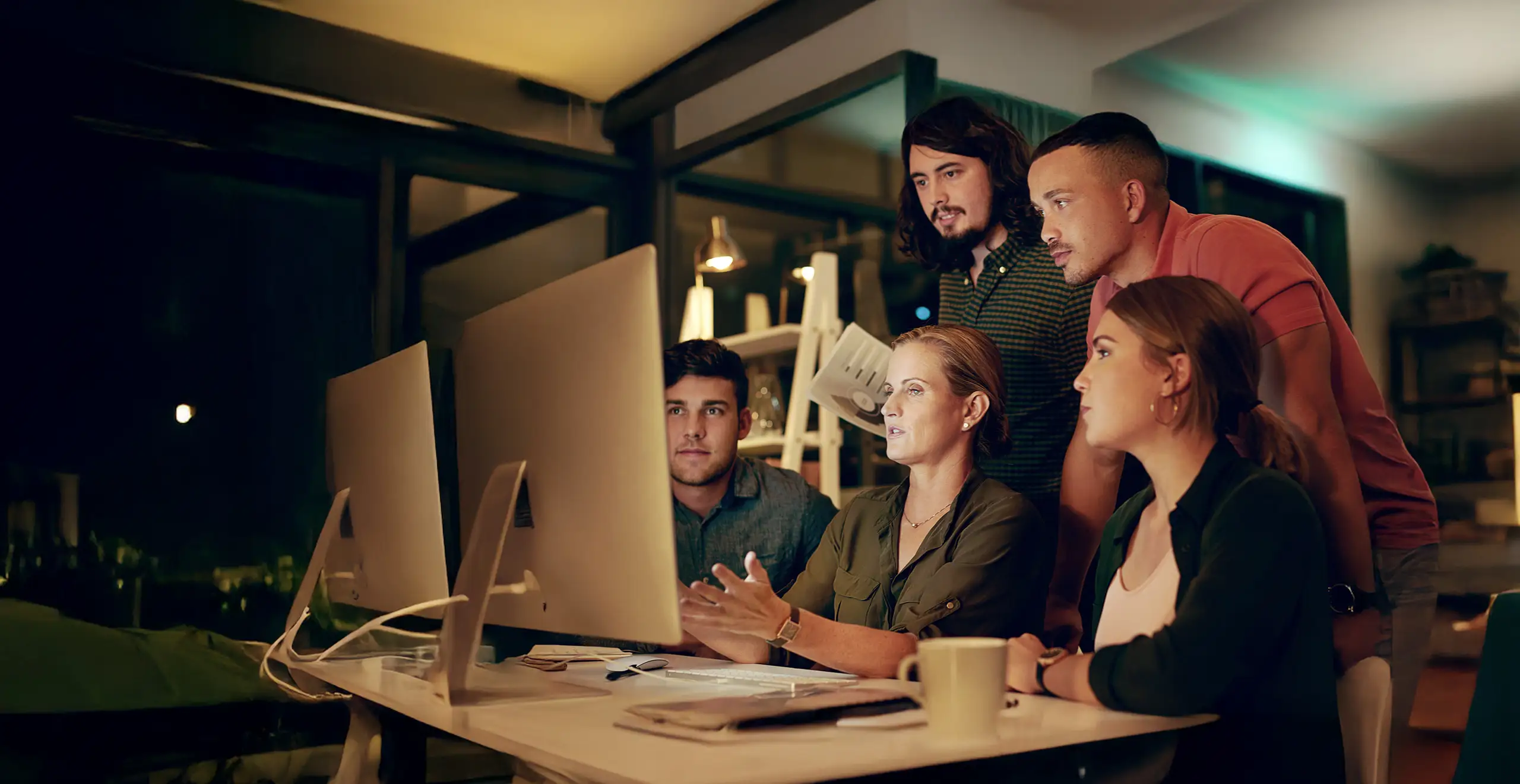 Group of professionals collaborating while viewing data on a large computer screen in a modern office